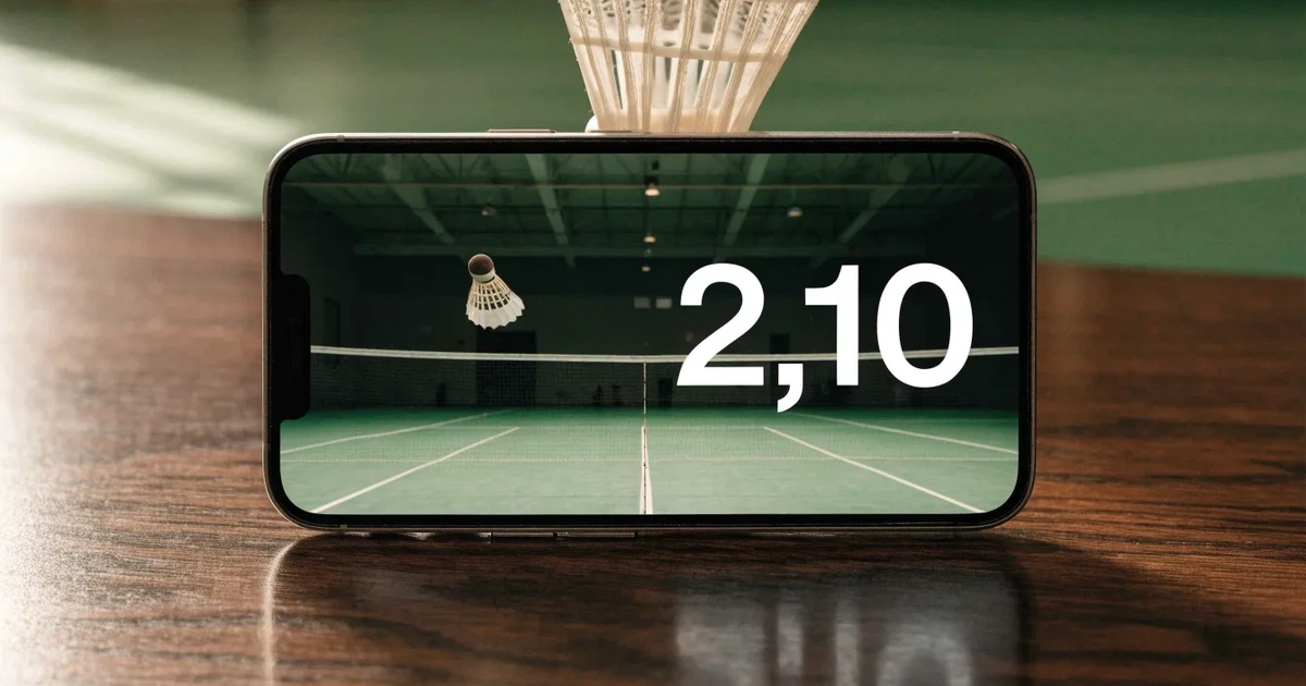 Eine leere Badmintonhalle mit gespanntem Netz und hellen Hallenlichtern, ein Federball liegt auf dem Hallenboden.